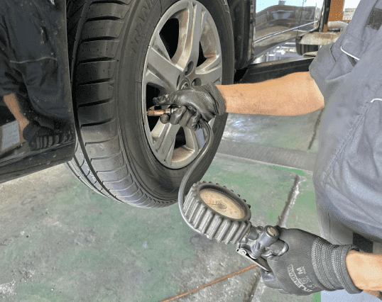 作業員がタイヤの空気圧を測定・調整している様子