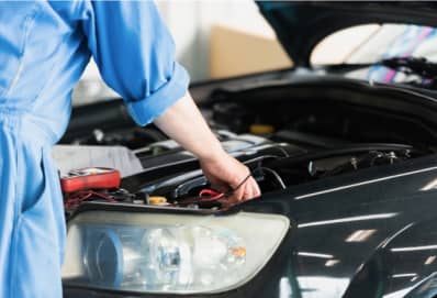 ボンネットを開けてエンジンルームをチェックする整備士