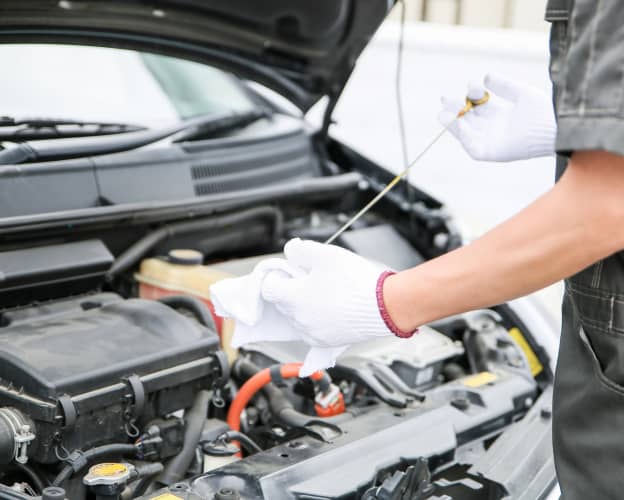 赤い作業着の整備士が車の下部を点検している様子