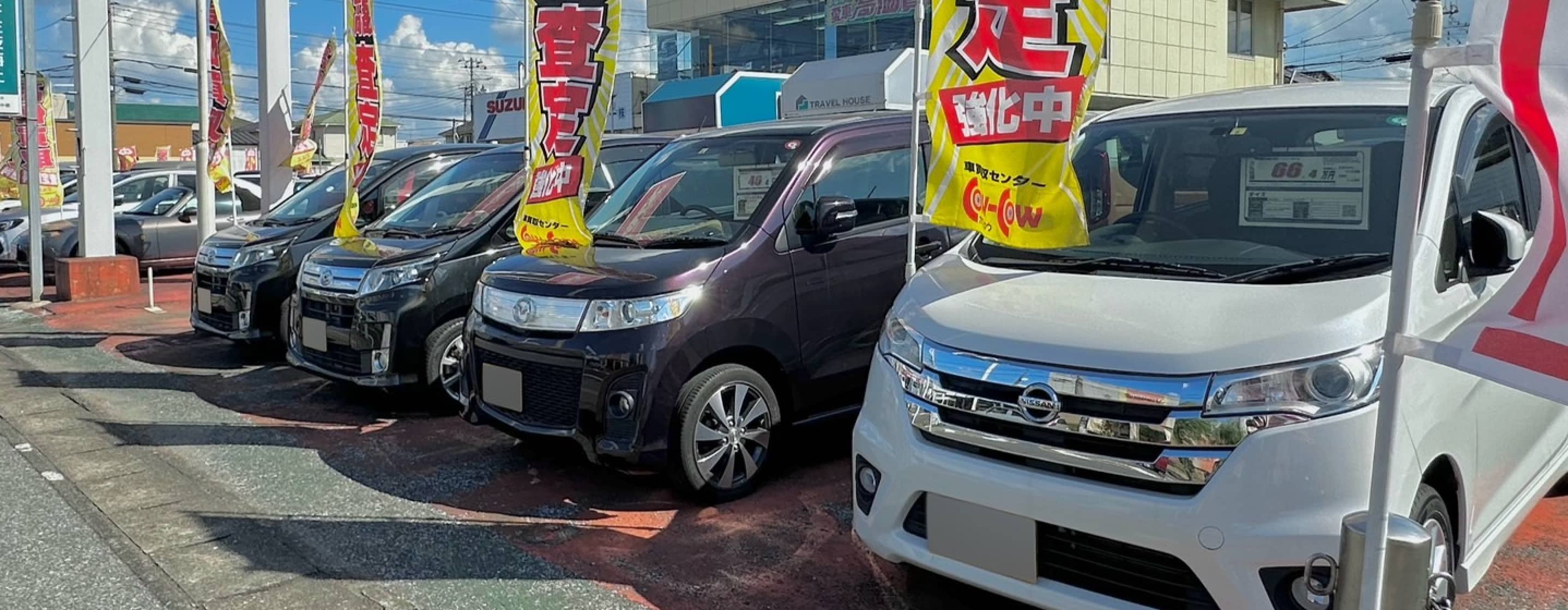 「査定強化中」ののぼりが立つ中古車販売店の展示場