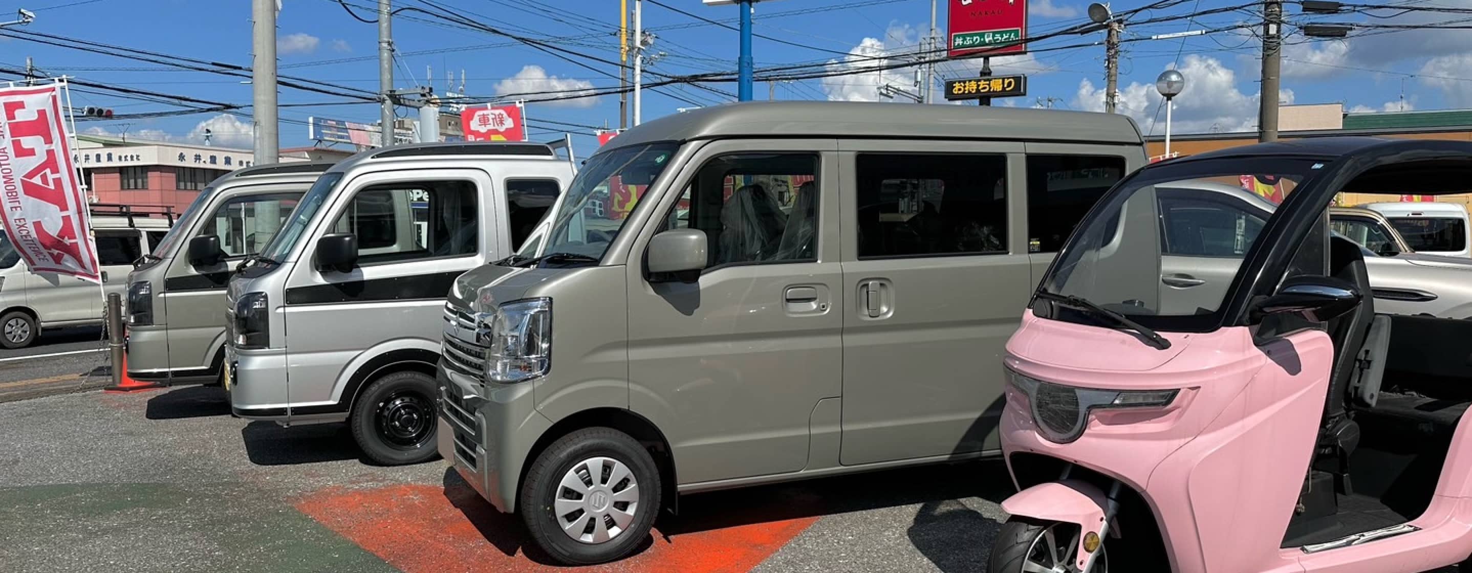 スズキの販売店に並ぶ軽自動車とピンクの電動三輪車