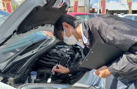 自動車のエンジンルームを点検するスタッフ