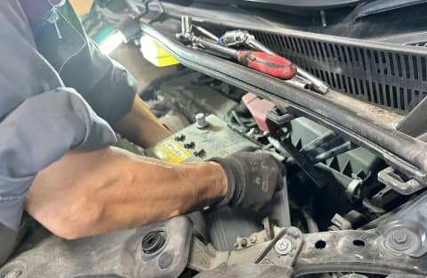 車のバッテリー付近を整備している整備士の手元